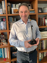 Harlan Stone thuis voor zijn boekenkast met de onderscheiding. (foto: I4F) harlan-stone-met-prijs