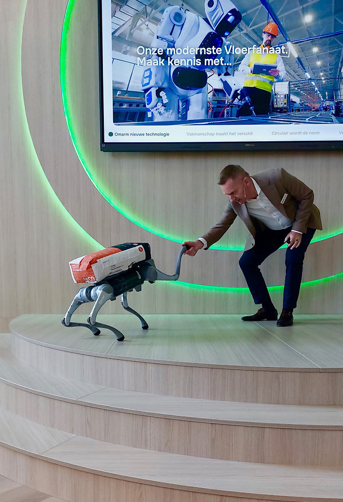 Robothondje ‘Co-tje’ brengt een zware zak egaline naar Klaas Bakker. Robothondje Kootje brengt een zware zak egaline naar Klaas Bakker